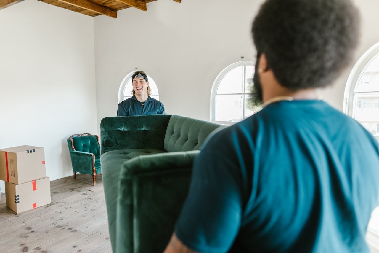 Crafting Captivating Headlines: Your awesome post title goes here Two movers carrying a green couch in a sunlit room with packed boxes.