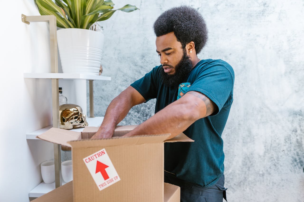 expertise-01 A professional mover packs a fragile item into a box in a stylish room.