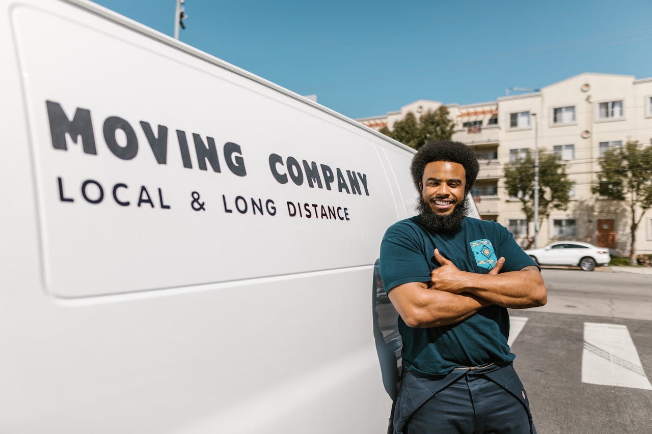 Home A cheerful mover standing confidently beside a moving companys van, ready for local or long distance relocation services.